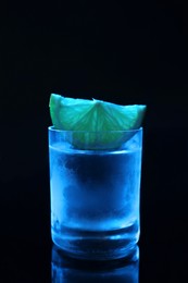 Photo of Shot glass of vodka with lime slice on dark background