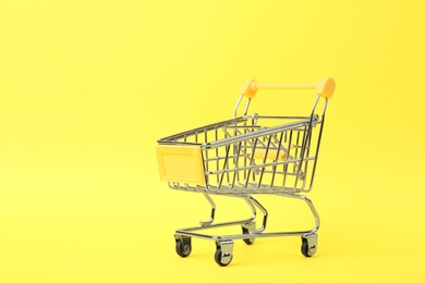 Photo of Empty shopping trolley on color background. Space for text