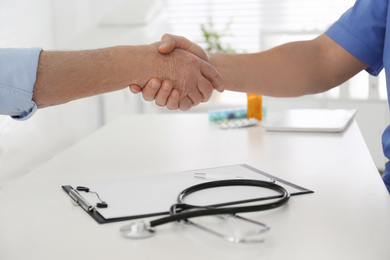 Photo of Doctor and senior patient shaking hands in office , closeup