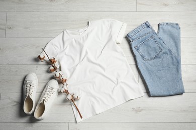 Stylish t-shirt, sneakers and jeans on white wooden background, flat lay