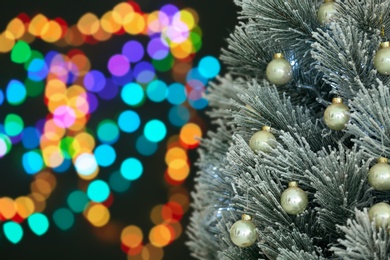 Photo of Decorated Christmas tree against blurred festive lights, closeup. Space for text