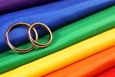 Wedding rings on rainbow LGBT flag, closeup