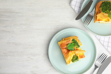 Photo of Tasty broccoli casserole served on white wooden table, flat lay. Space for text