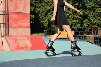 Photo of Woman doing exercises in kangoo jumping boots in workout park, closeup