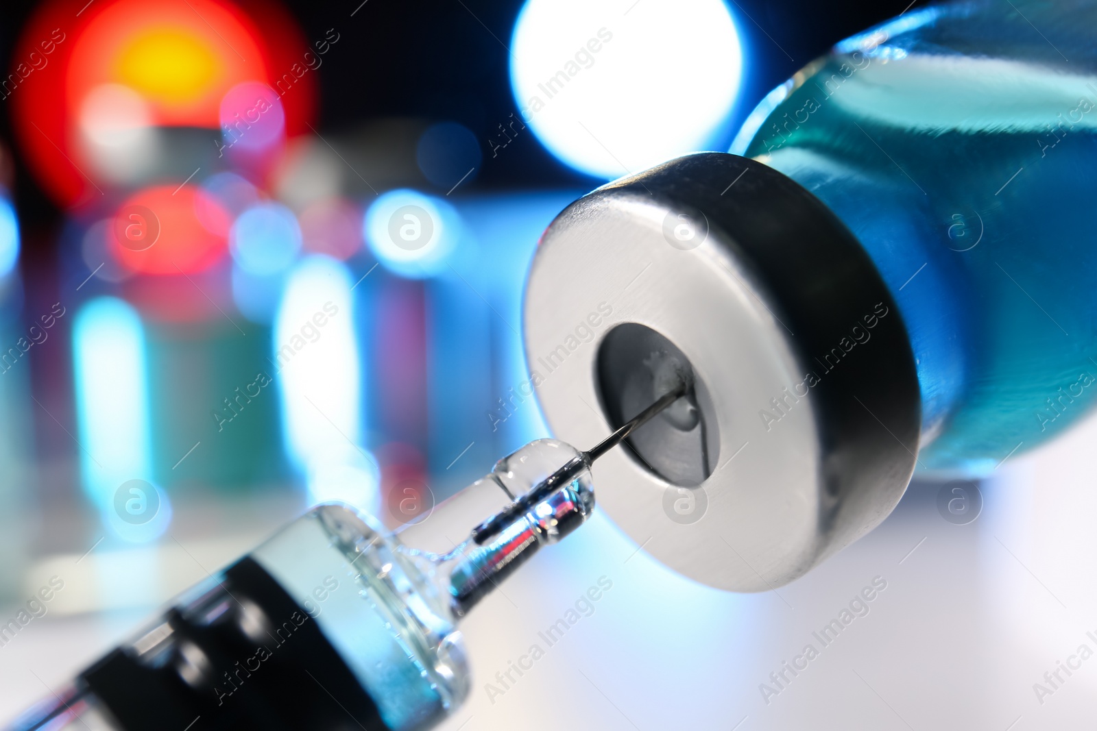 Photo of Filling syringe with vaccine from vial on blurred background, closeup