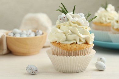 Photo of Tasty Easter cupcake with vanilla cream on light wooden table