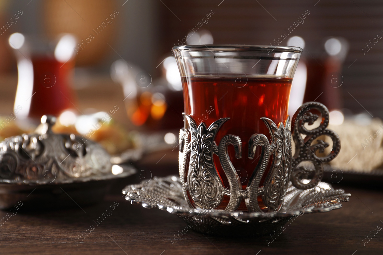 Photo of Glass of traditional Turkish tea in vintage holder on wooden table, closeup. Space for text