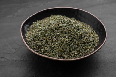 Bowl with dried thyme on black table, closeup