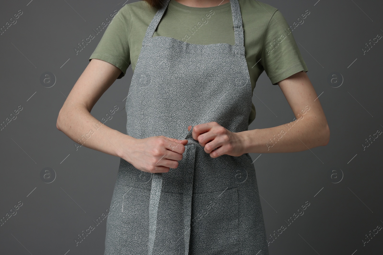 Photo of Woman wearing kitchen apron on grey background, closeup. Mockup for design