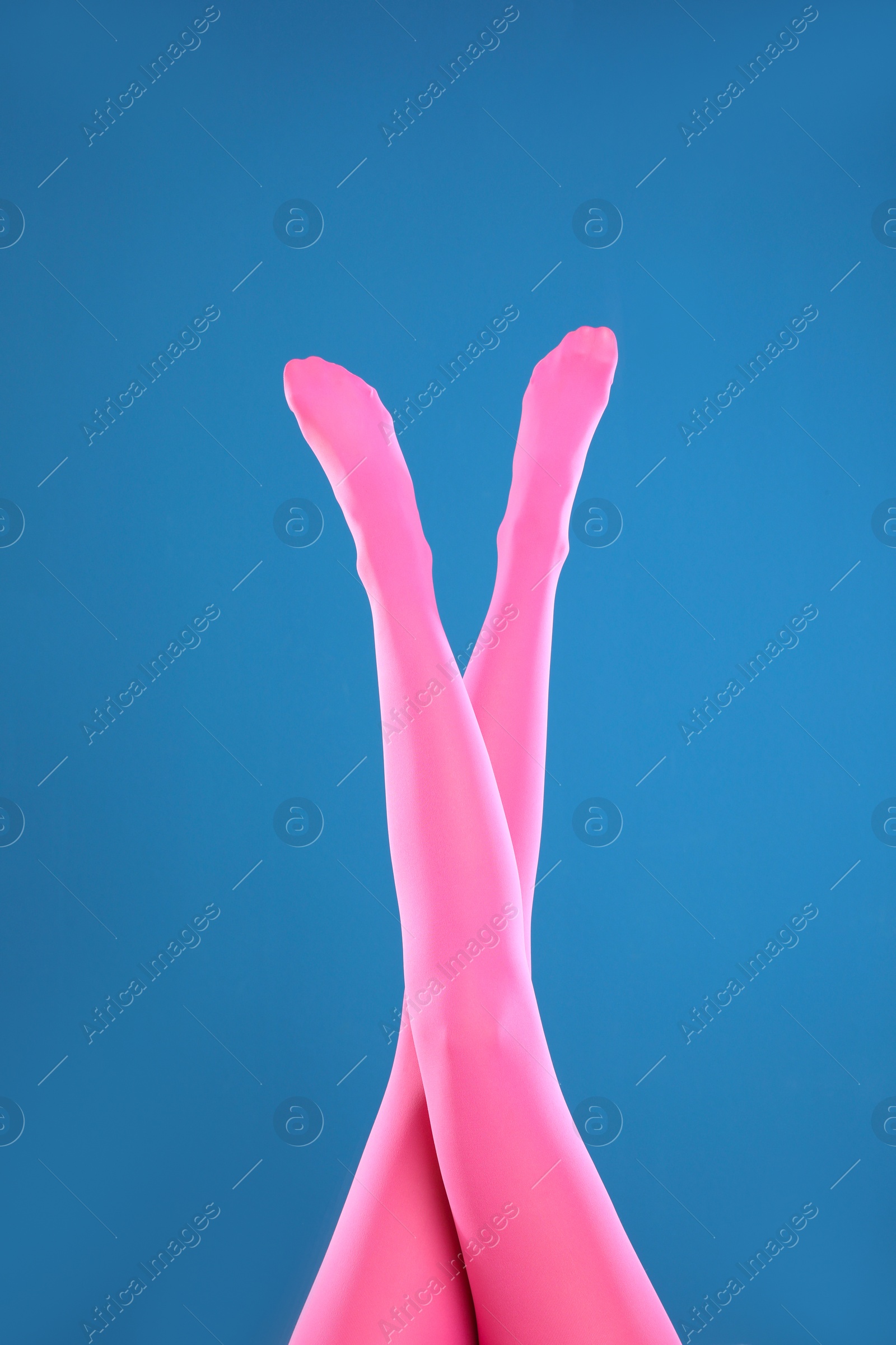 Photo of Woman wearing pink tights on blue background, closeup of legs