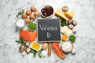 Photo of Flat lay composition with products rich in vitamin D on white marble table