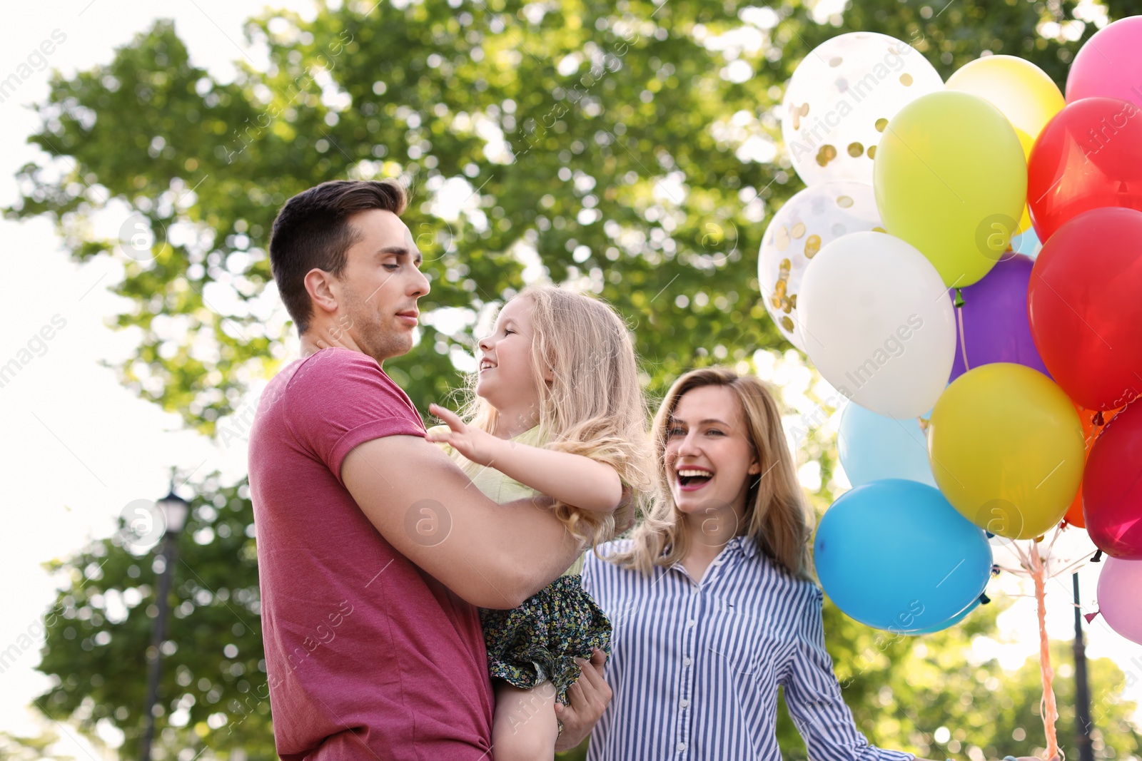 Photo of Happy family with colorful balloons outdoors on sunny day