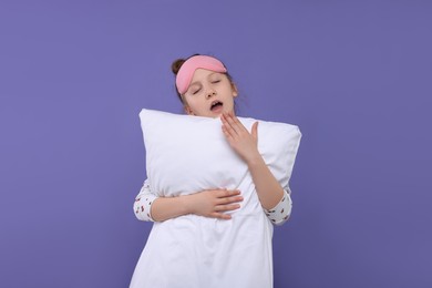 Girl with sleep mask and pillow yawning on purple background. Insomnia problem