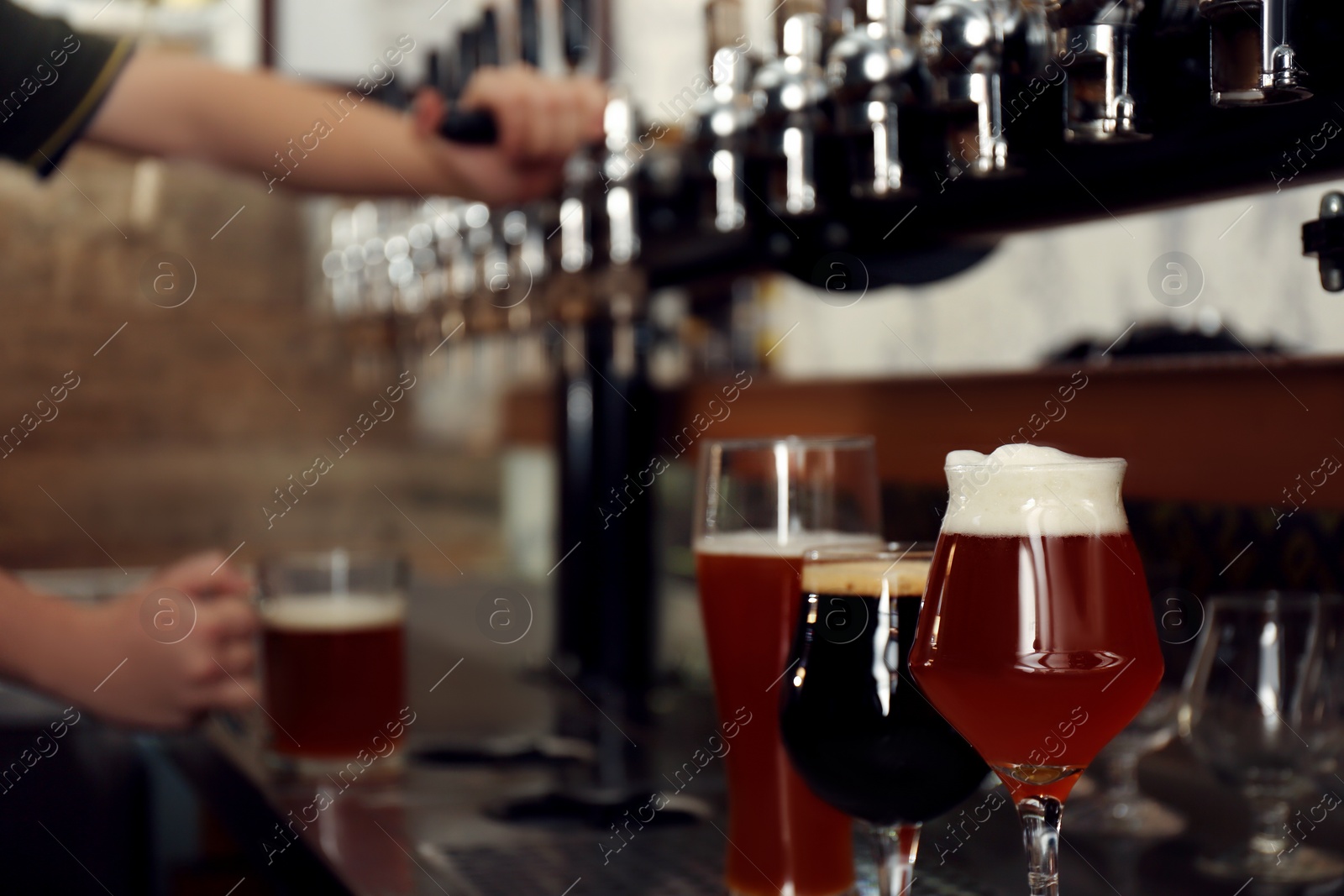 Photo of Different beers in glasses on bar counter, space for text