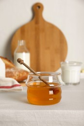 Photo of Jar with honey, milk and bread served for breakfast on table