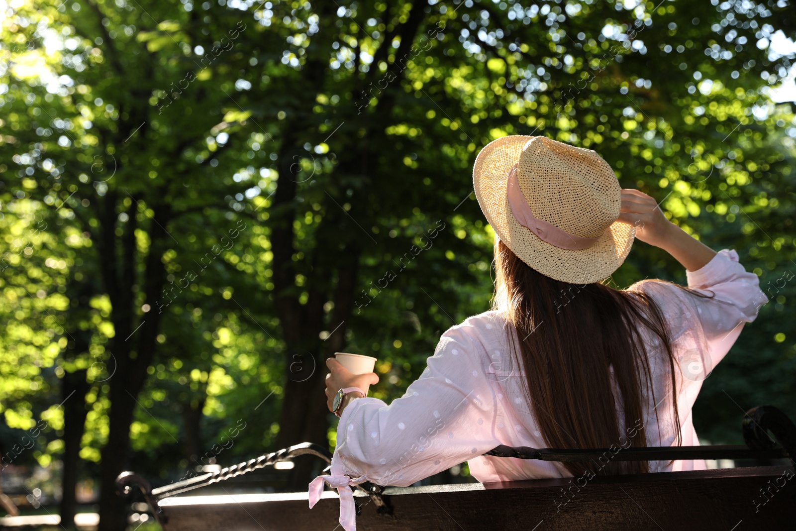 Photo of Woman with drink in park on sunny day, back view. Space for text