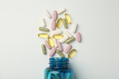 Photo of Vitamin pills and bottle on light background, top view