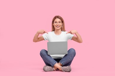 Photo of Happy woman pointing on laptop against pink background
