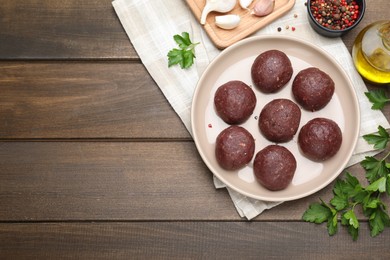 Photo of Many fresh raw meatballs and ingredients on wooden table, flat lay. Space for text