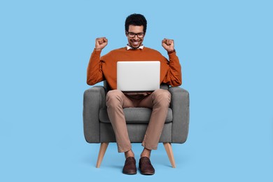 Photo of Emotional man with laptop sitting in armchair on light blue background