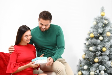 Happy young couple with Christmas gift at home