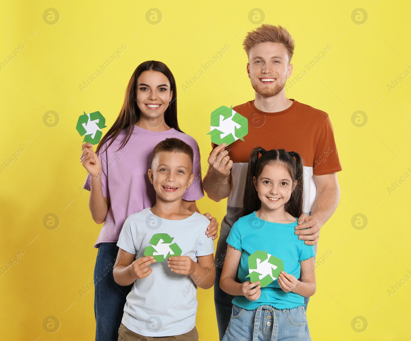 Photo of Young family with recycling symbols on yellow background