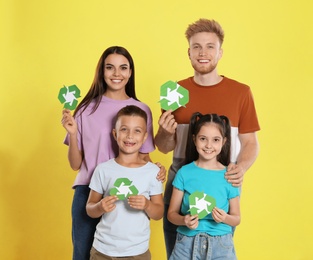 Photo of Young family with recycling symbols on yellow background