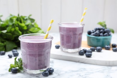 Tasty blueberry smoothie with mint and fresh berries on white marble table. Space for text