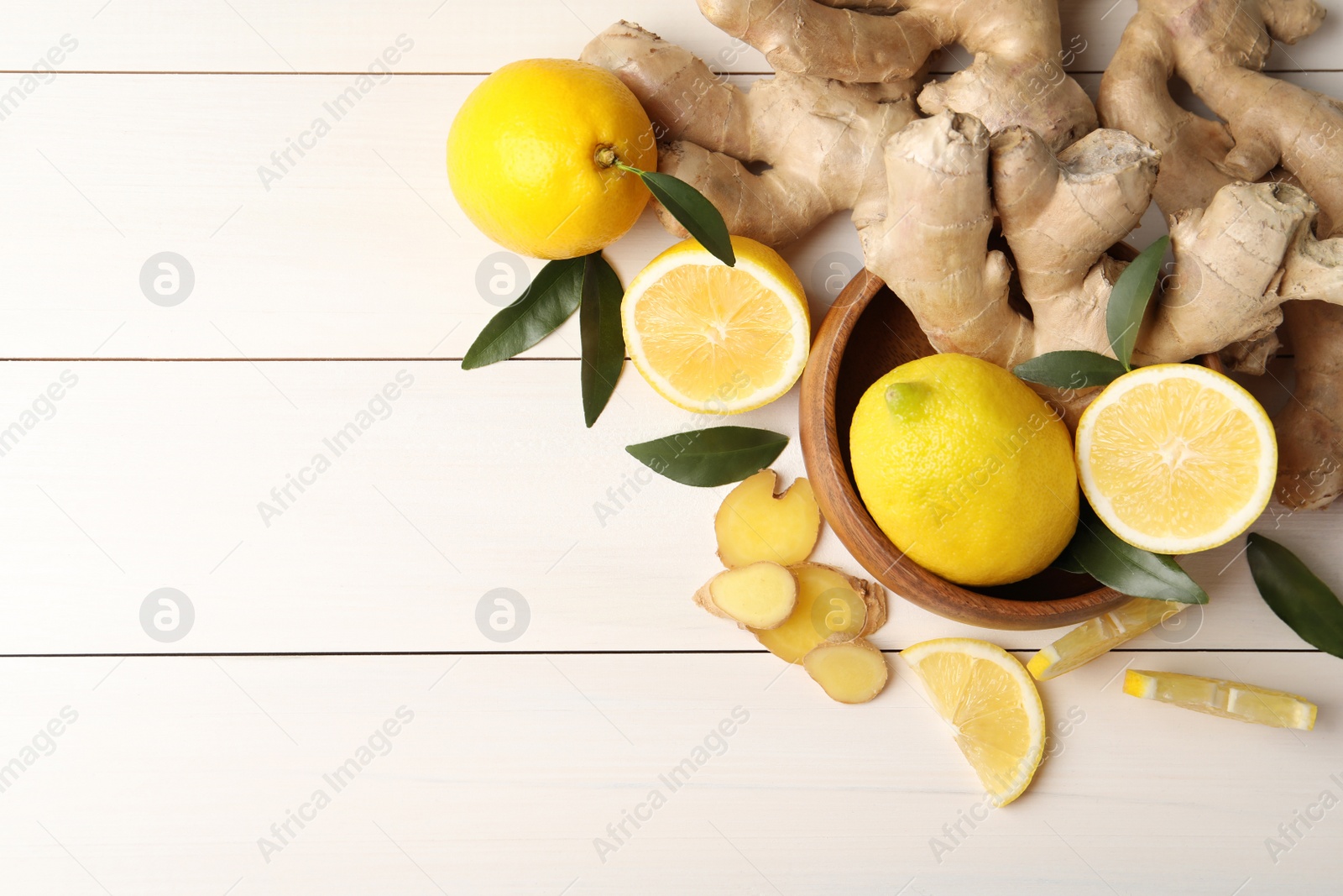 Photo of Fresh lemons and ginger on white wooden table, flat lay. Space for text