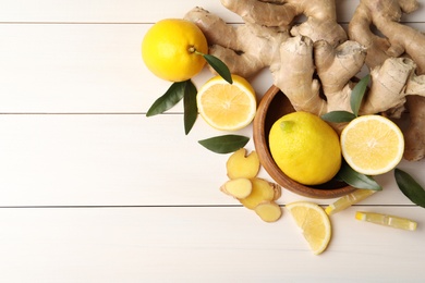 Photo of Fresh lemons and ginger on white wooden table, flat lay. Space for text