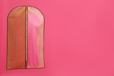 Photo of Garment bag with dress on pink background. Space for text