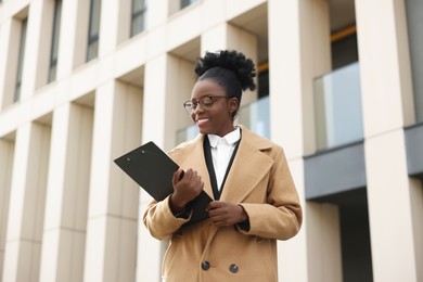 Photo of Happy woman with clipboard outdoors. Lawyer, businesswoman, accountant or manager