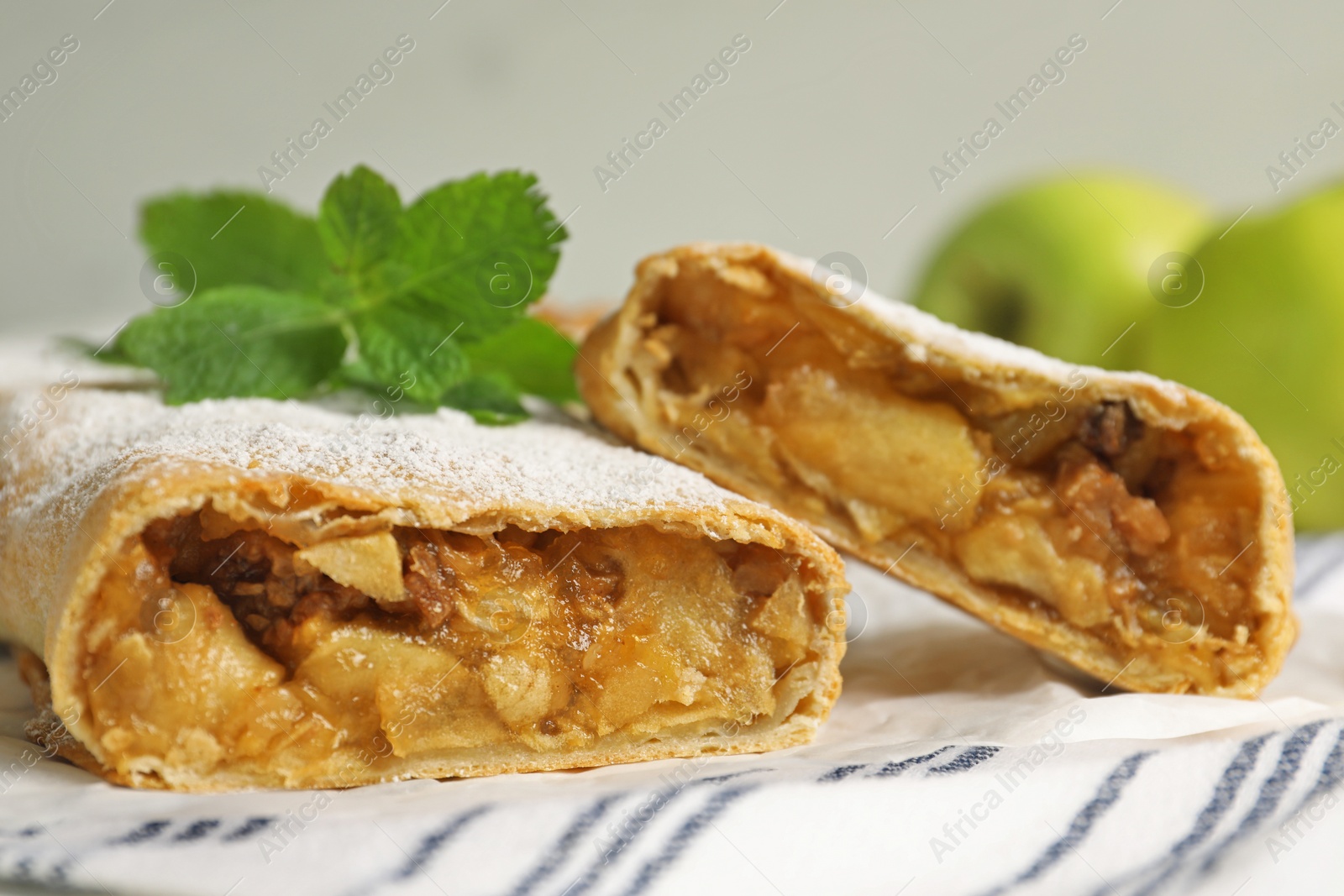 Photo of Delicious strudel with apples, nuts and powdered sugar on table, closeup