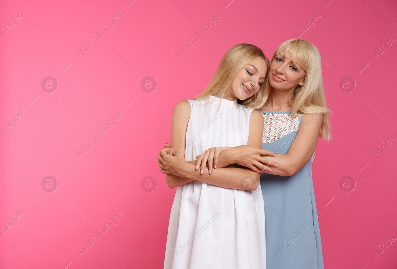 Photo of Portrait of young woman with her mature mother on pink background, space for text