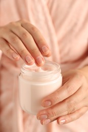 Photo of Woman holding jar of hand cream, closeup