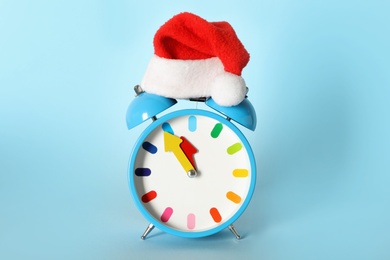 Alarm clock with Christmas decor on light blue background. New Year countdown
