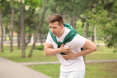 Photo of Young man having chest pain outdoors. Heart attack