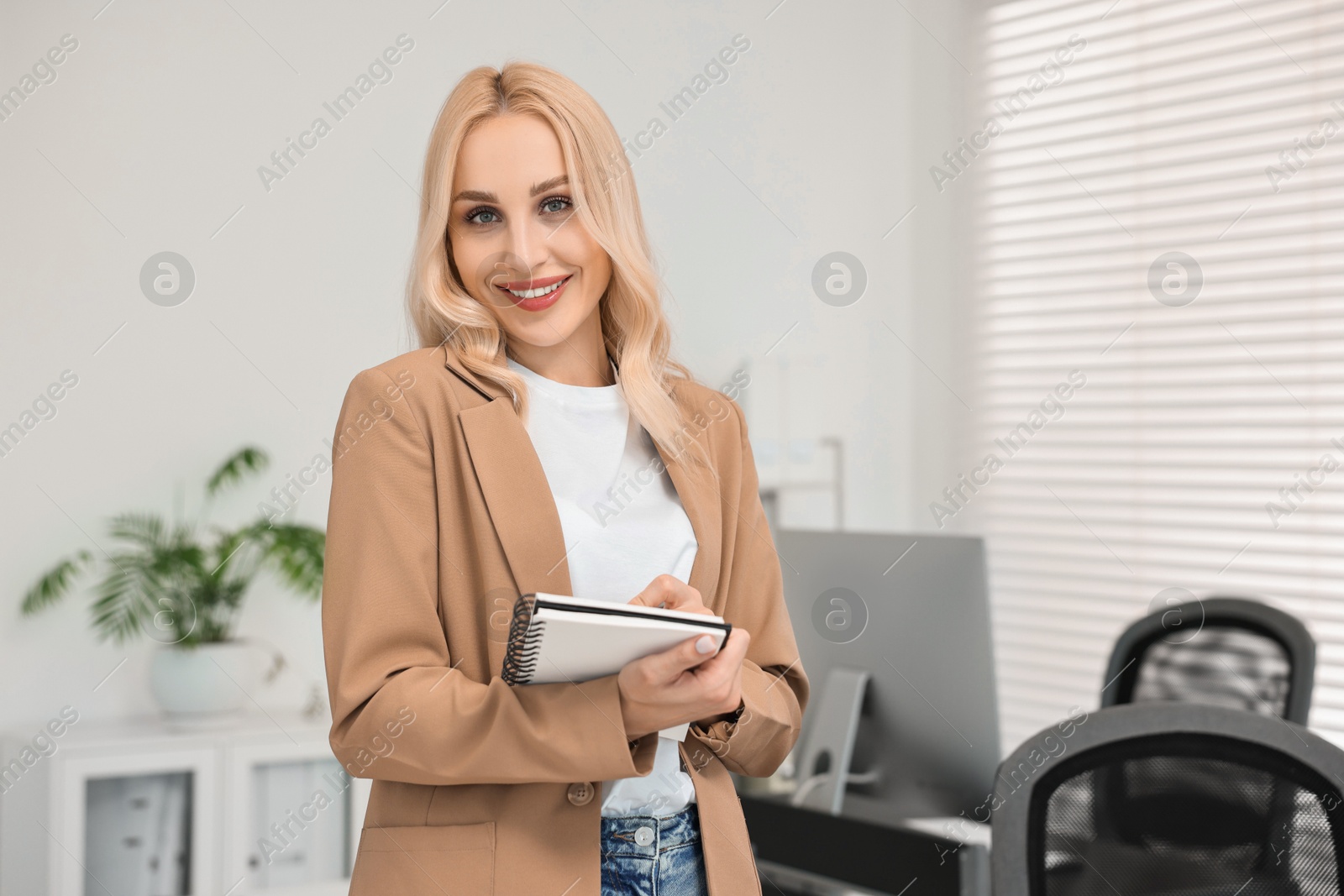 Photo of Happy secretary with notebook in office, space for text