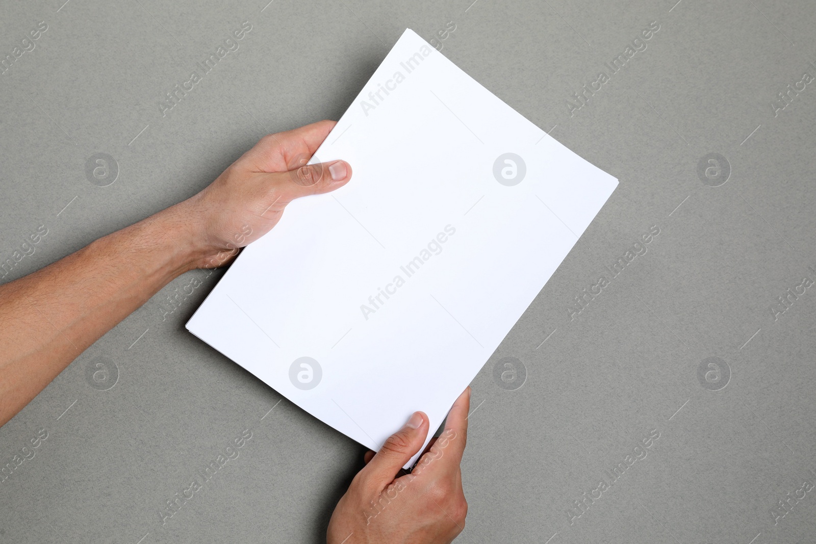 Photo of Man holding sheets of paper on grey background, closeup. Mockup for design