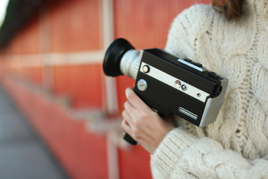 Beautiful young woman with vintage video camera outdoors, closeup of hand