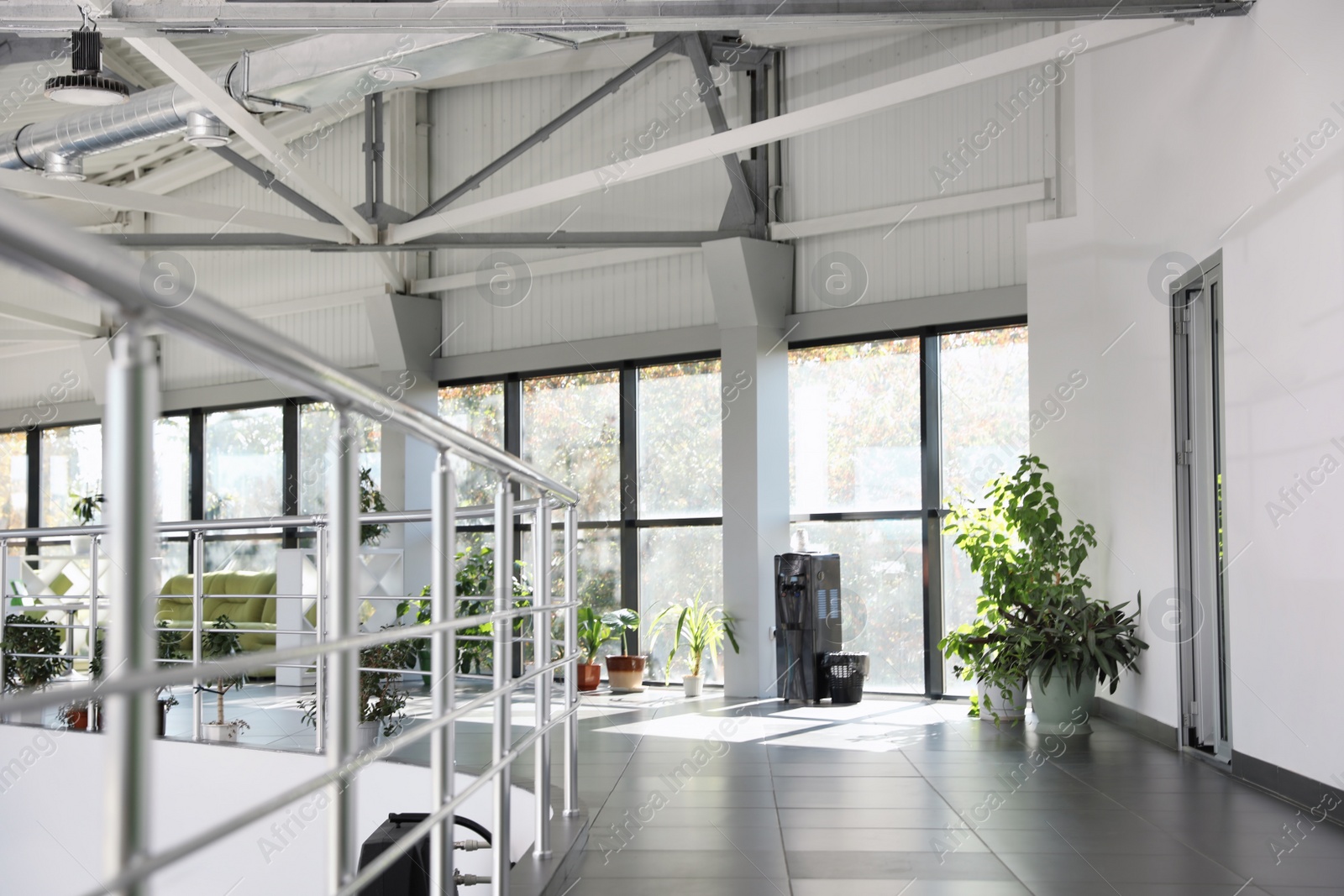 Photo of Modern office interior with water cooler, sofa and large windows