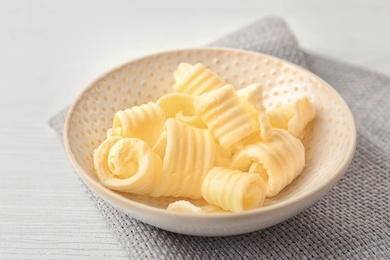 Plate with fresh butter curls on table