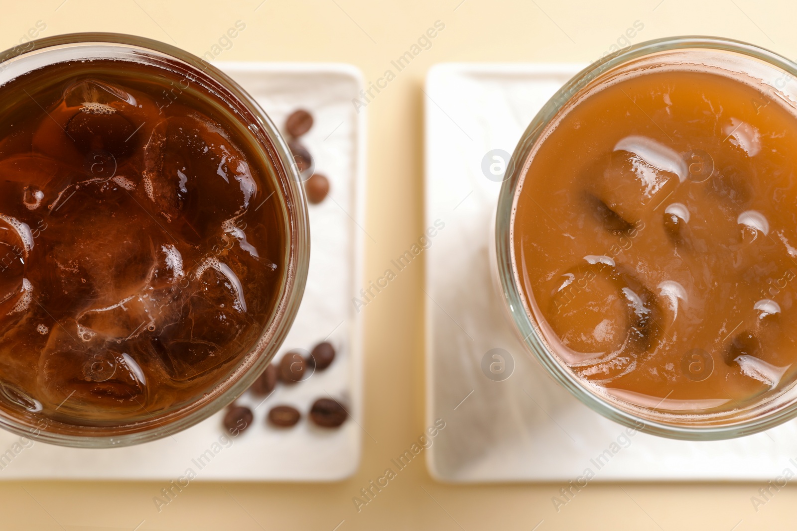 Photo of Refreshing iced coffee with milk in glasses on beige table, flat lay