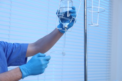 Photo of Nurse setting up IV drip in hospital, closeup. Space for text