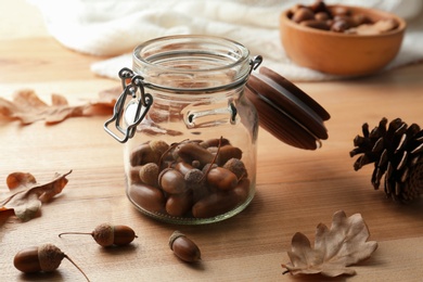 Photo of Acorns, oak leaves and pine cone on wooden table