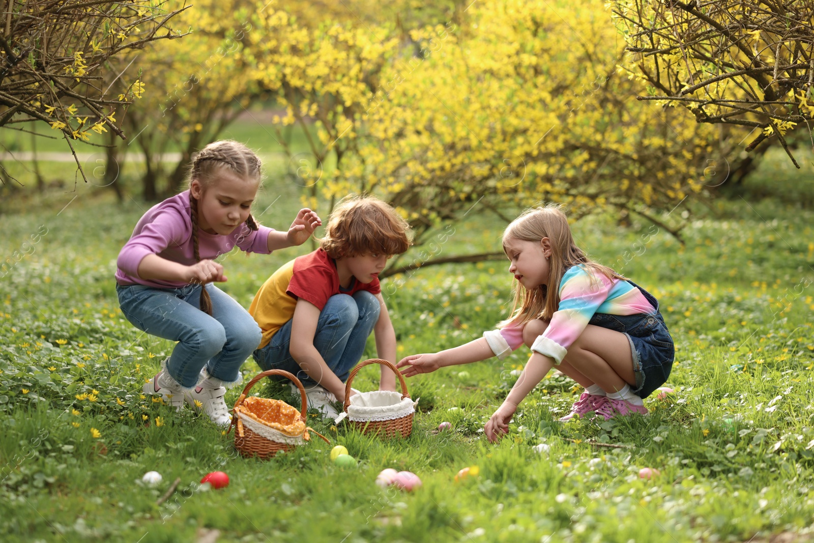 Photo of Easter celebration. Cute little children hunting eggs outdoors