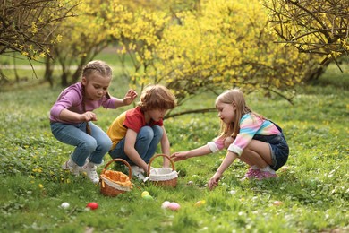 Easter celebration. Cute little children hunting eggs outdoors