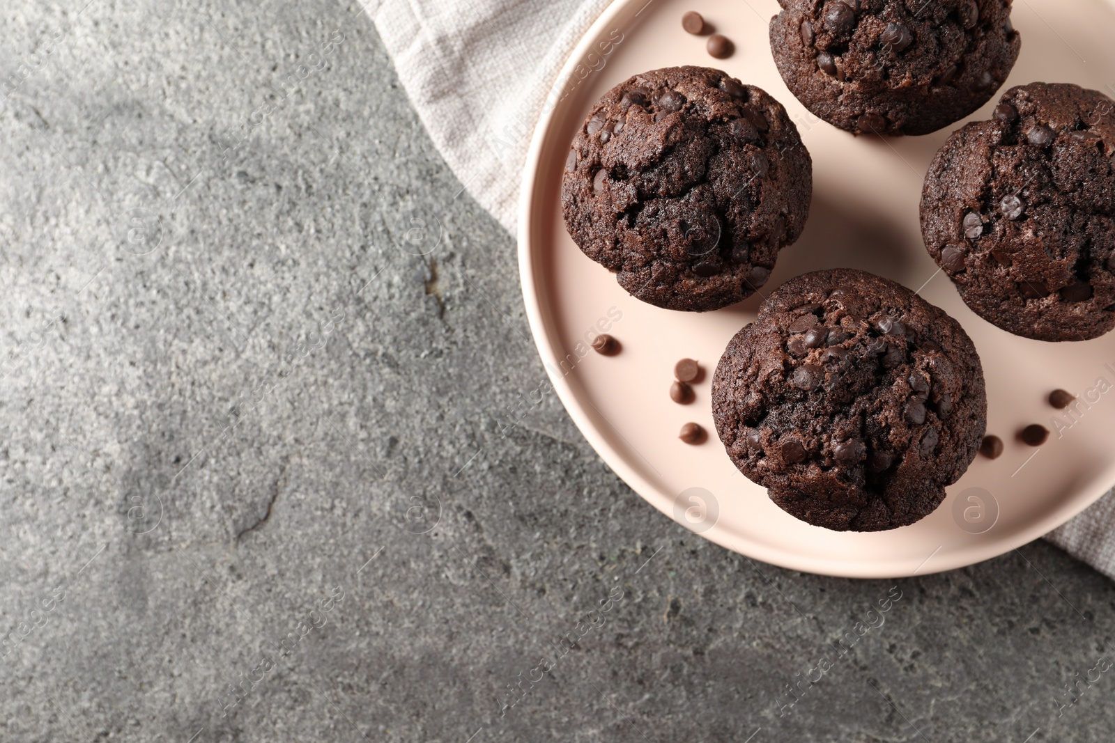 Photo of Delicious chocolate muffins on grey textured table, top view. Space for text