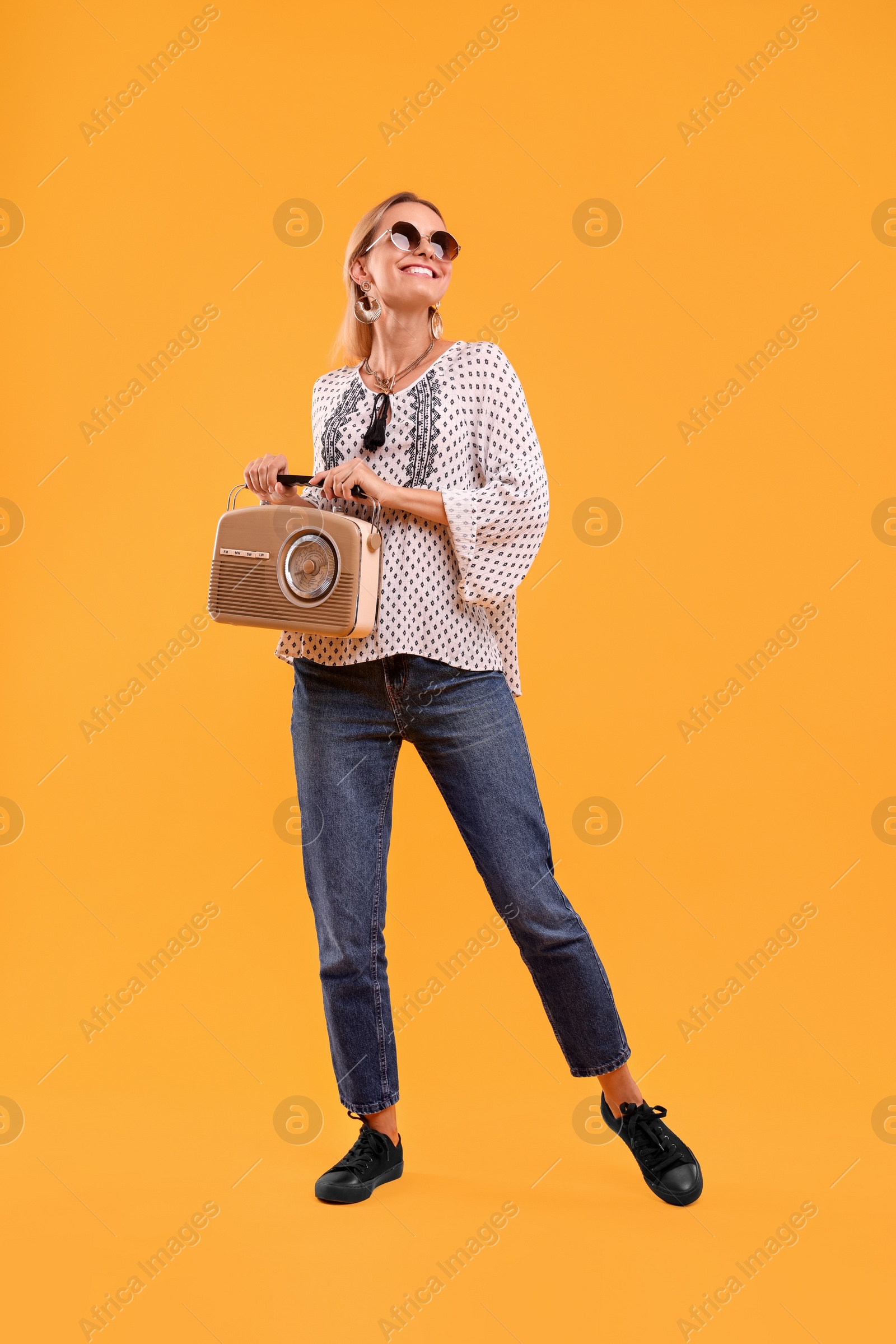 Photo of Portrait of happy hippie woman with retro radio receiver on yellow background