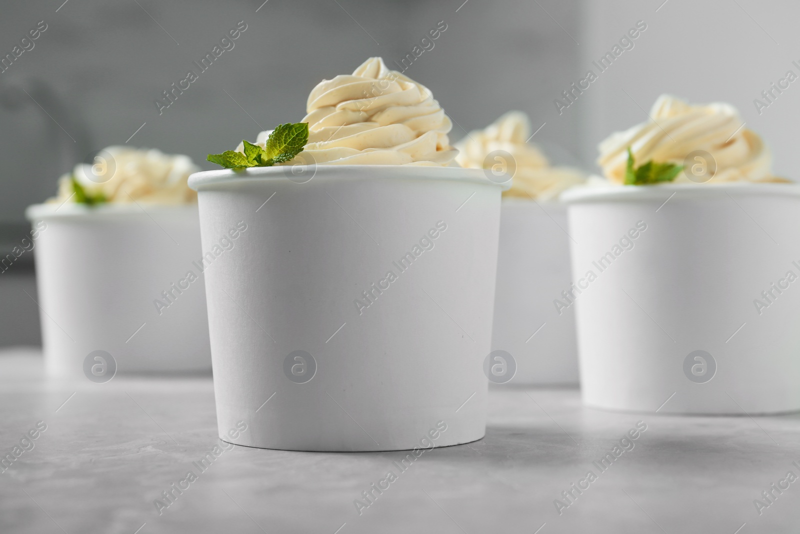 Photo of Cups with tasty frozen yogurt on grey table indoors